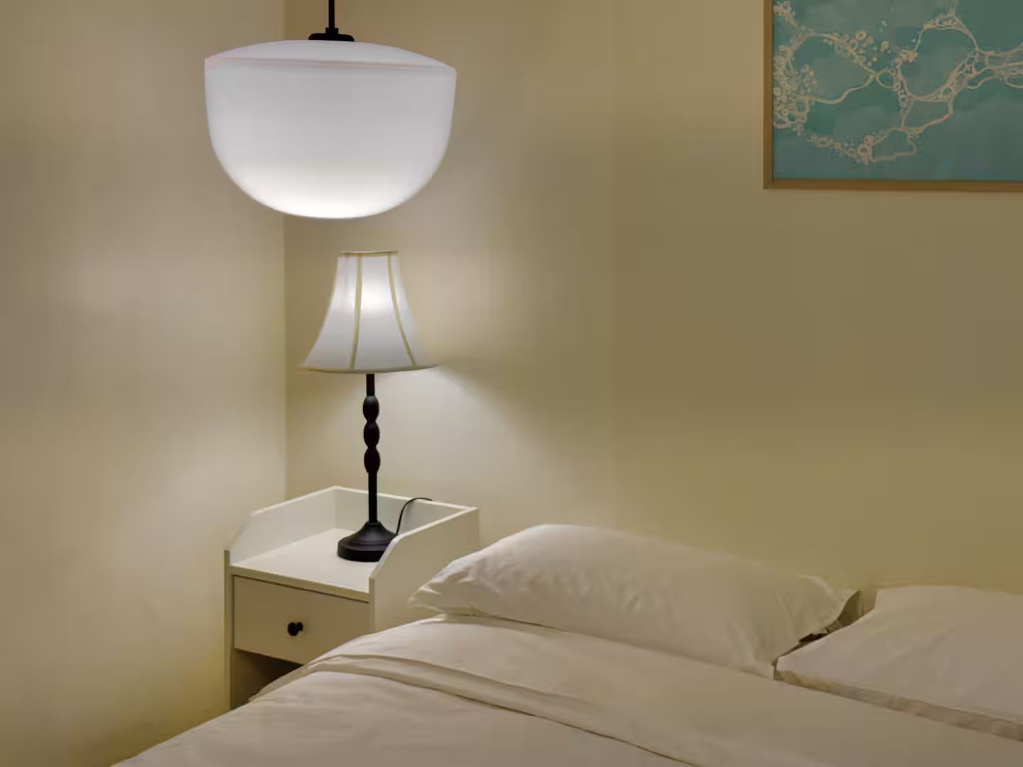 A hotel room with a bed, a nightstand, a lamp, and a wall-mounted light fixture.