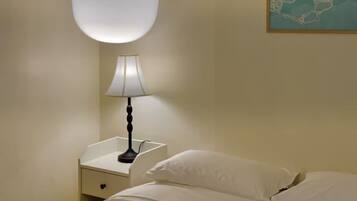 A hotel room with a bed, a nightstand, a lamp, and a wall-mounted light fixture.