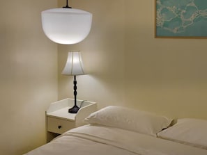 A hotel room with a bed, a nightstand, a lamp, and a wall-mounted light fixture. - Jagalchi Mansion (Busan)