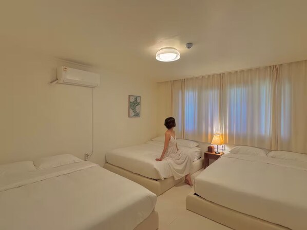 Habitación de hotel con dos camas, una mesita de noche con lámpara e iluminación en el techo.