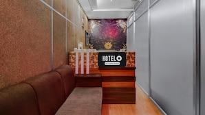 A hotel reception area with a wooden reception desk, a plush seating area, and a decorative wall mural. - Hotel O Cooch Behar (Cooch Behar)