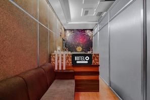 Un'area reception di un hotel con una scrivania in legno, una zona salotto confortevole e un murale decorativo.