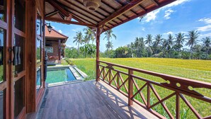 Um deck de madeira com piscina e vista para um campo de arroz.