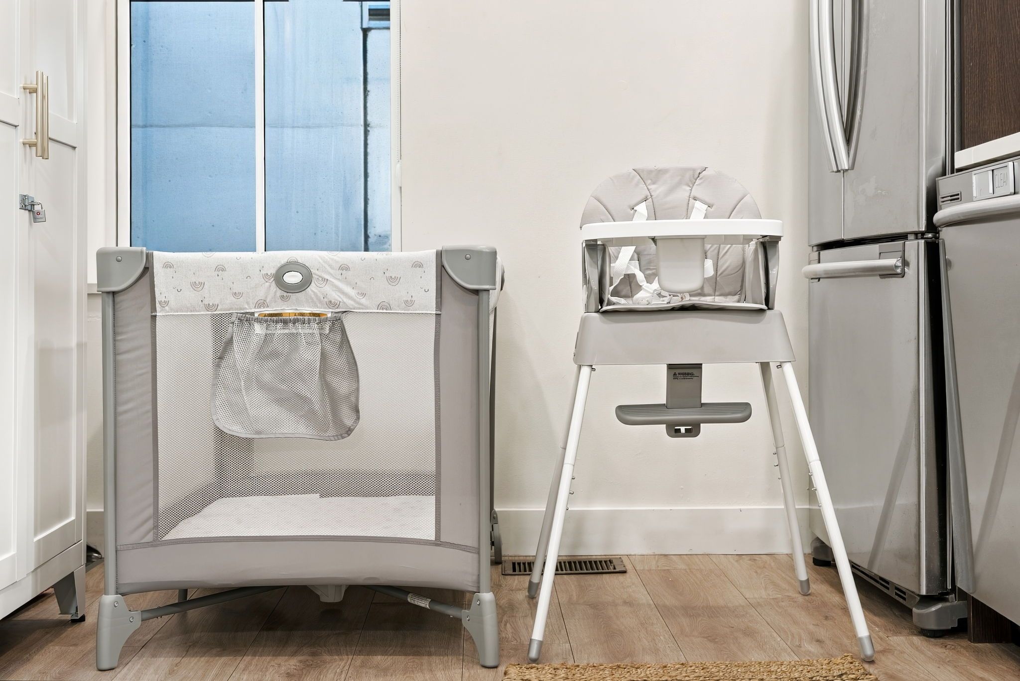 A kitchen with a high chair, a baby gate, and a refrigerator.