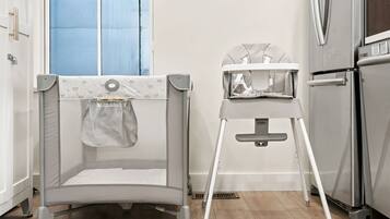 A kitchen with a high chair, a baby gate, and a refrigerator.