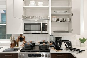 Une cuisine moderne équipée d’un four à micro-ondes encastré, d’une cuisinière et de divers appareils de cuisine.