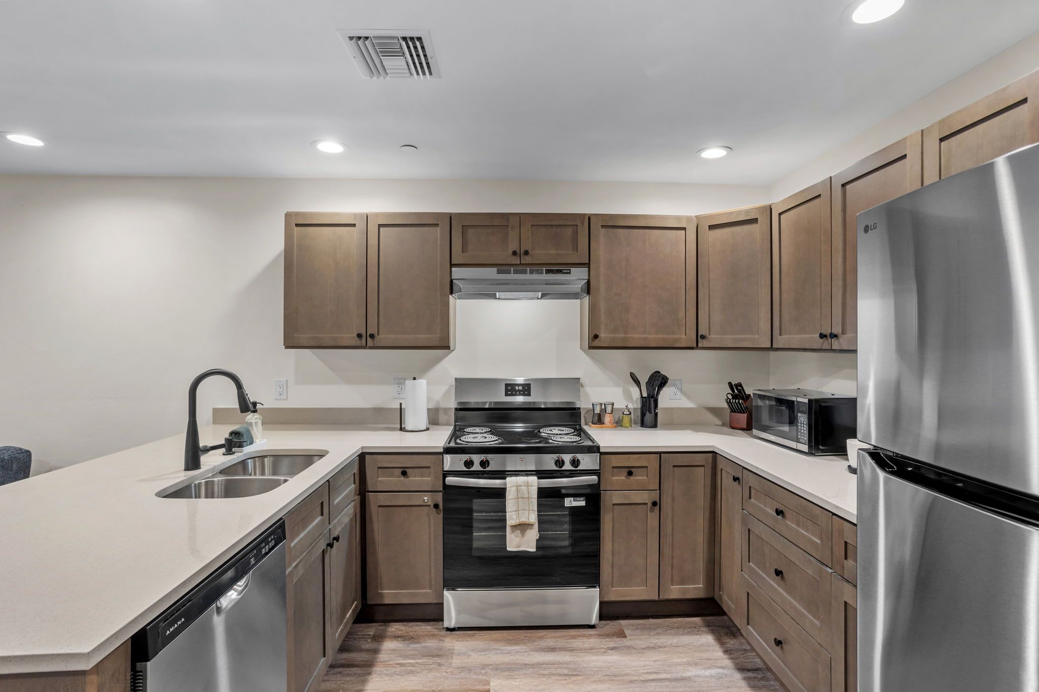 A modern kitchen with stainless steel appliances, wooden cabinets, and a dishwasher.
