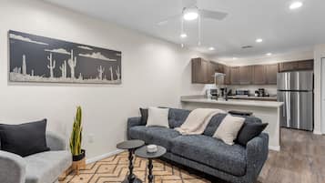 A modern living room with a grey sofa, a coffee table, and a large painting on the wall.