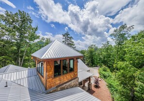 A modern house with a sloped roof, large windows, and a stone foundation. - Castle Rock Luxury Cabin with Smoky Mt Views (Bryson City)