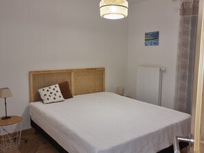Ein Schlafzimmer mit einem Bett, einem Nachttisch, einer Lampe, einem Heizkörper und einem Bild an der Wand.