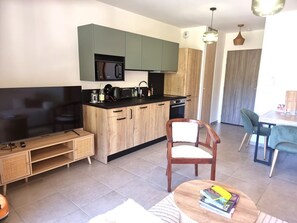 Eine moderne Küche mit Flachbildfernseher, Holzschränken und einem Essbereich mit Tisch und Stühlen.