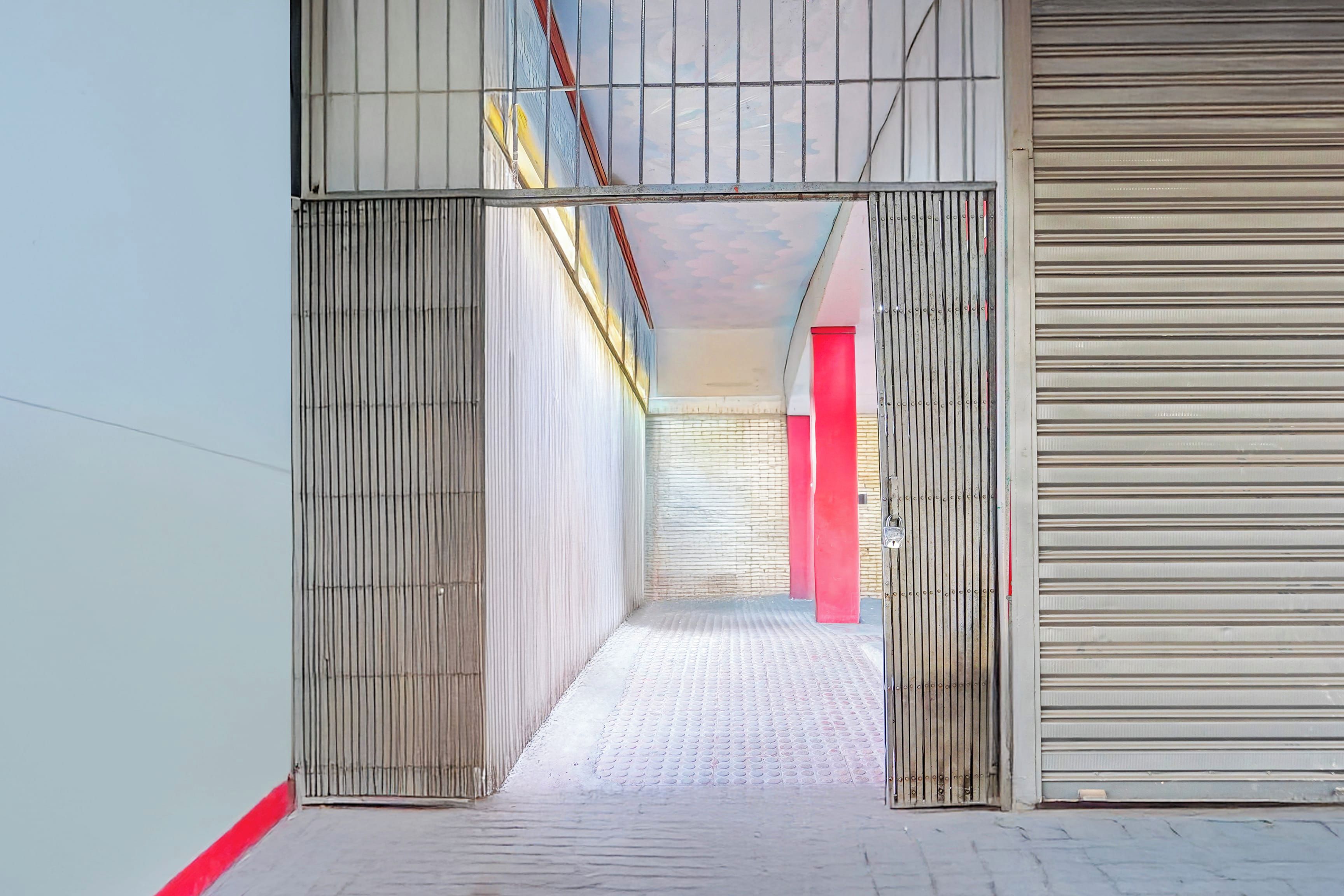 A corridor with a metal gate, a red pillar, and a closed shutter door.