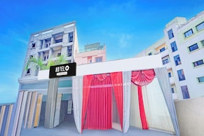 Entrada de hotel com placa, fachada de edifício moderno e céu claro.