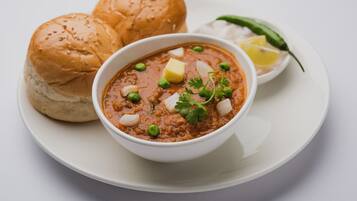Eine Schüssel Curry mit Brot und einem Zitronenschnitz auf einem Teller.