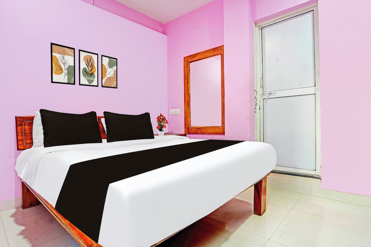 Quarto com cama, mesa de cabeceira, espelho e três quadros na parede.