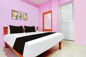 Quarto com cama, mesa de cabeceira, espelho e três quadros na parede.