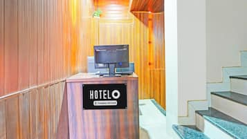Una recepción de hotel con un cartel que dice 'HOTELO Company-Serviced' y un televisor encima.