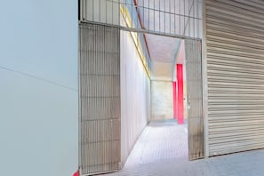 Un pasillo con barandales de metal y una puerta con contraventana cerrada.