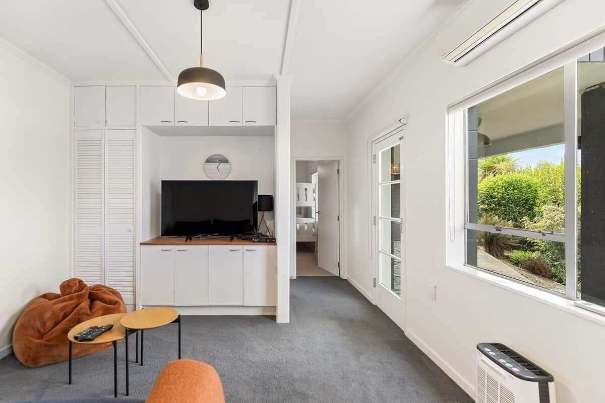 Ein moderner Wohnraum mit Küche, Essbereich und großem Fenster mit Blick auf Grünflächen.