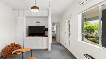 Ein moderner Wohnraum mit Küche, Essbereich und großem Fenster mit Blick auf Grünflächen.