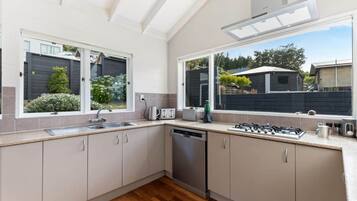 A modern kitchen with a dishwasher, stove, and large windows.