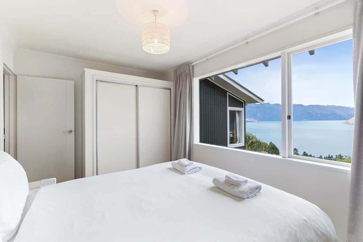 A hotel room with a large bed, a view of the sea, and a chandelier.