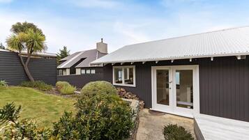 Ein modernes Haus mit dunkler Fassade, einem gepflegten Rasen und einer Holzterrasse.