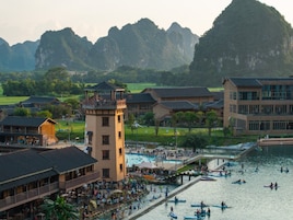 Un complejo turístico con una piscina, una torre y edificios tradicionales.