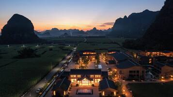 A hotel with a central courtyard, surrounded by buildings, set against a mountainous backdrop.