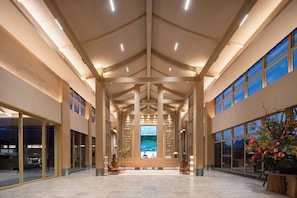 A spacious lobby with a high ceiling, large windows, and a reception desk.