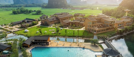 A resort with multiple buildings, a swimming pool, and a river.