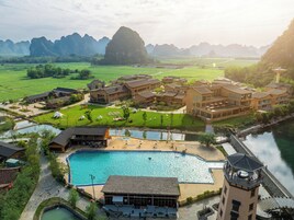 Un resort con varias edificaciones, piscina y un río.