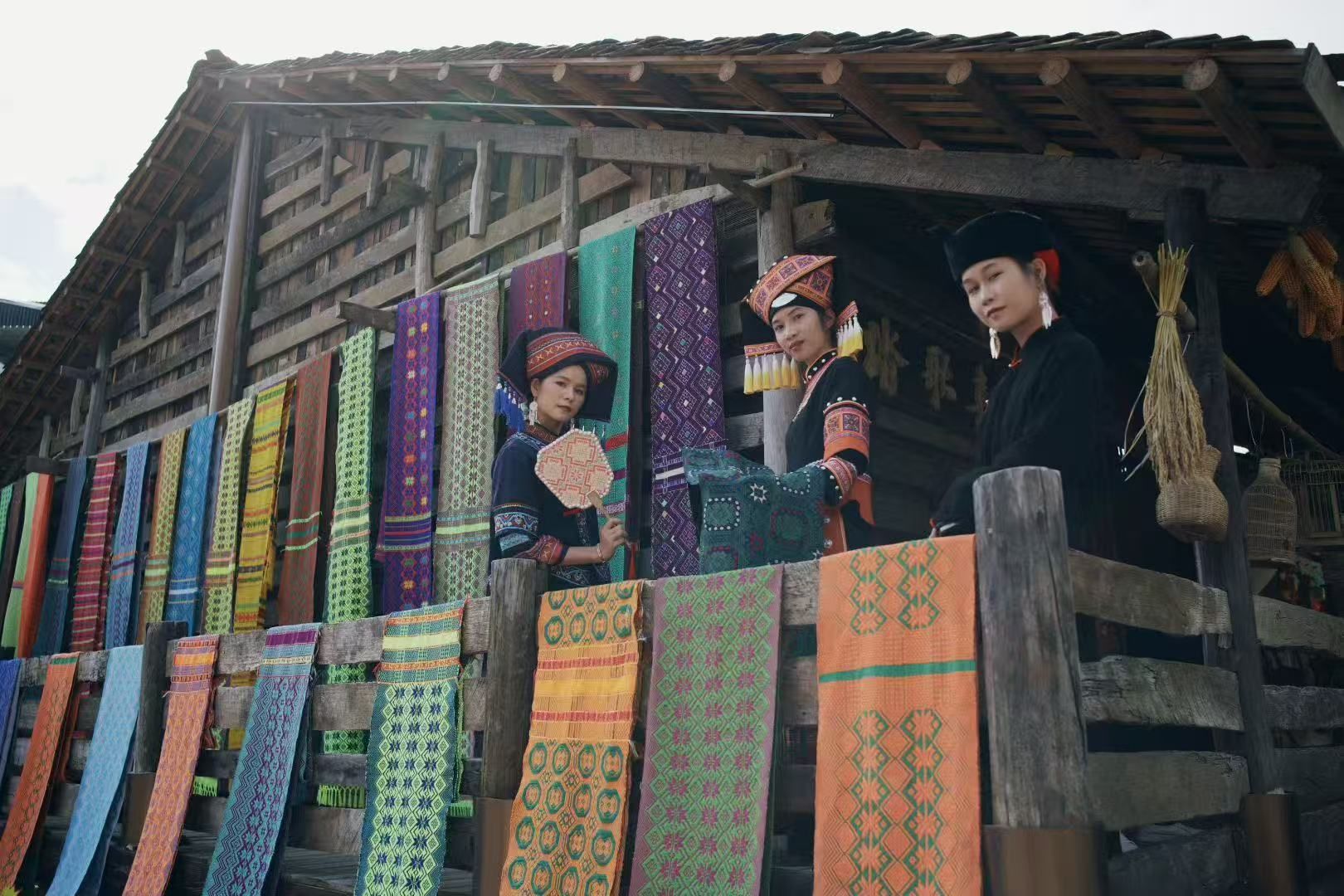 Un edificio tradicional con fachada de madera y textiles coloridos expuestos en el exterior.