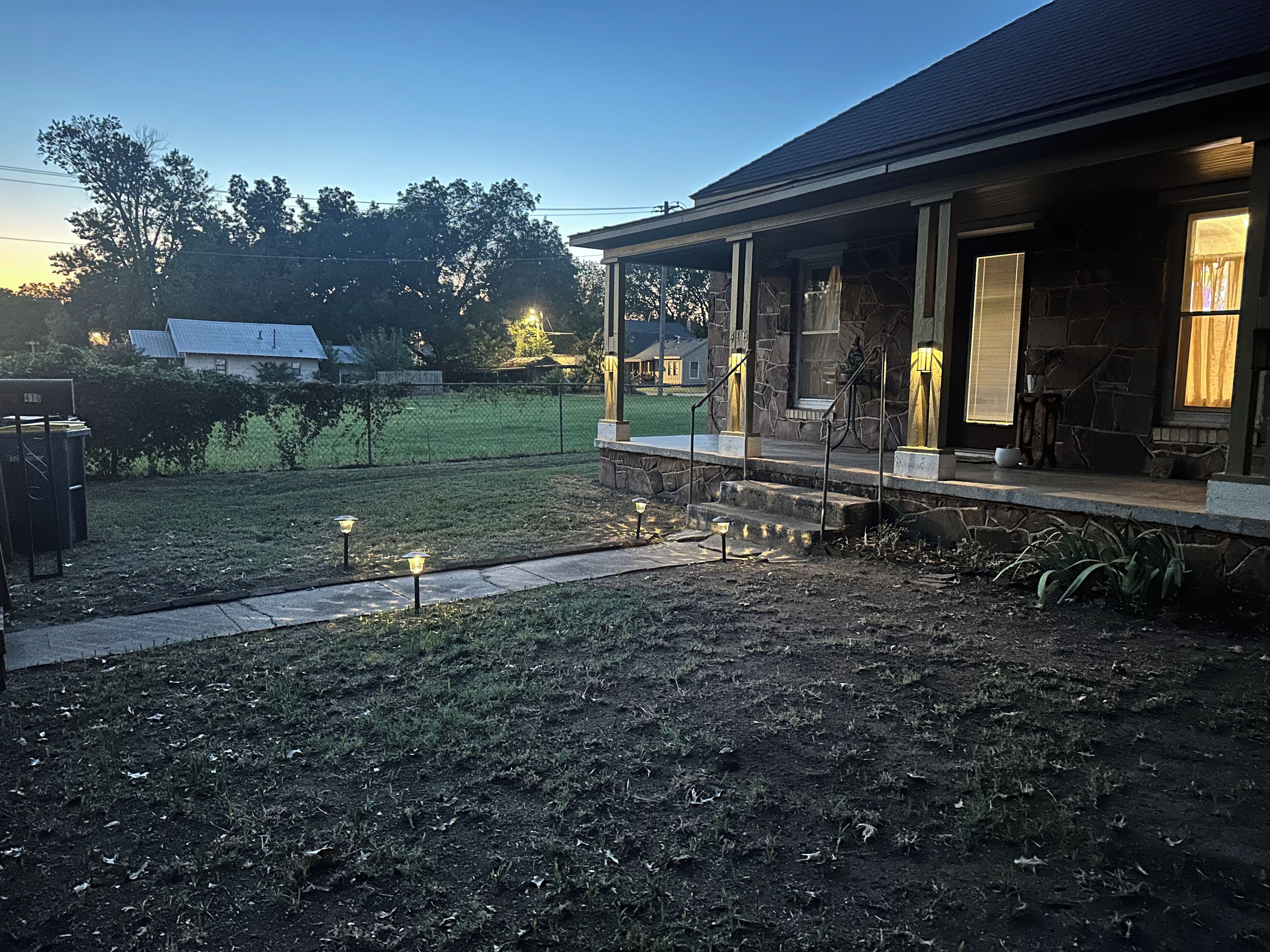 A house with a covered porch, a stone exterior, and a lawn with a pathway.