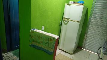 A small room with a green wall, a white refrigerator, and a blue door.