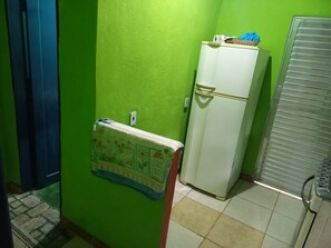A small room with a green wall, a white refrigerator, and a blue door.