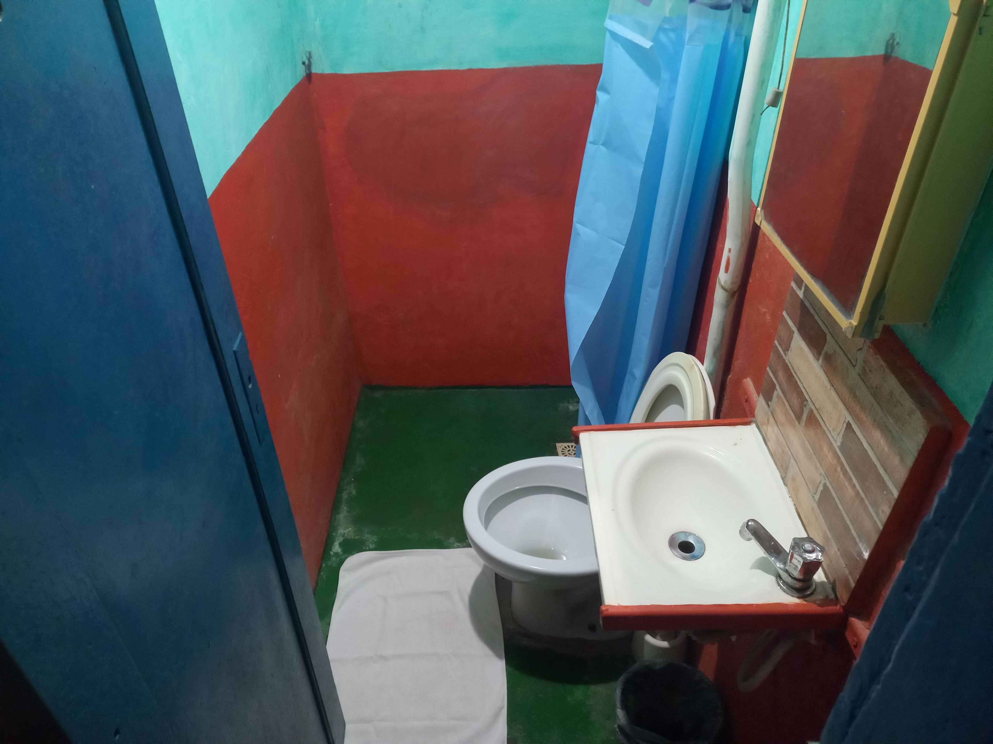 Et lille, aflangt badeværelse med toilet, vask og spejl.