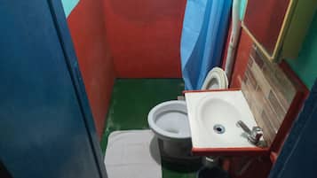 Et lille, aflangt badeværelse med toilet, vask og spejl.