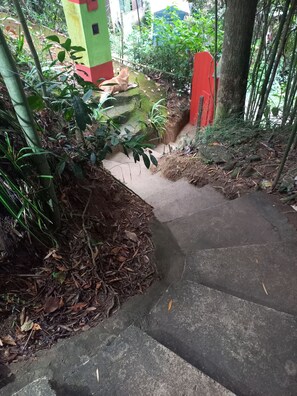 En støbt trappe omgivet af vegetation og et rødt gelænder.