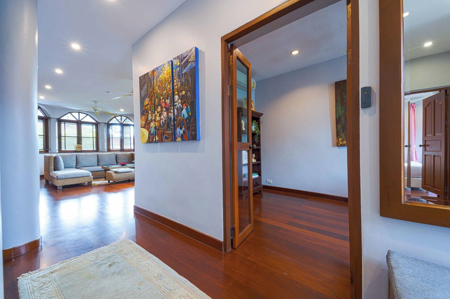 A spacious living room with a large painting, a sofa set, and a wooden floor.