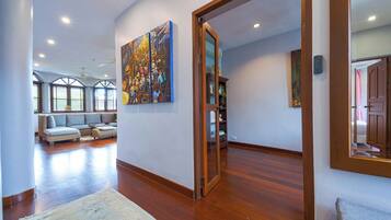 A spacious living room with a large painting, a sofa set, and a wooden floor.