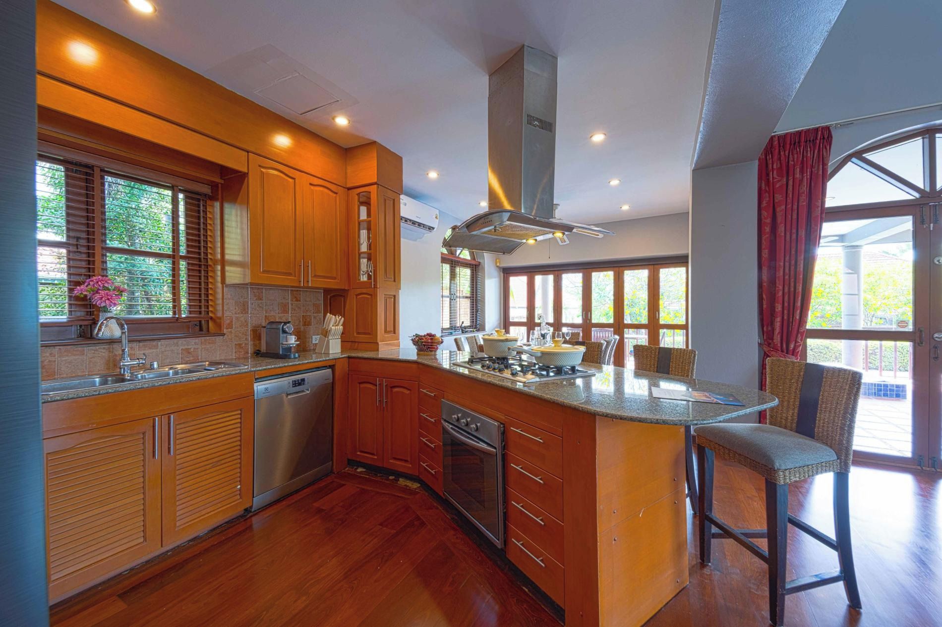A spacious kitchen with wooden cabinets, a large island, and a dining area with wicker chairs.