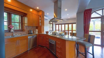 A spacious kitchen with wooden cabinets, a large island, and a dining area with wicker chairs.