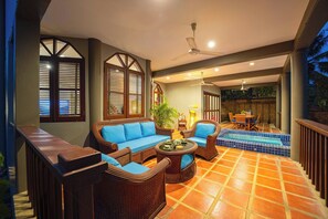 Un espacio interior amplio con piscina, zonas de estar y ventilador de techo.