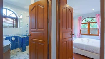 Une chambre avec un lit, une salle de bain avec un lavabo et un miroir, et une fenêtre avec des rideaux.