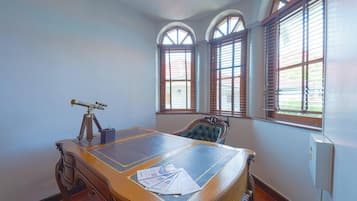 A room with a large wooden table, a telescope, and a chair with a leather seat.