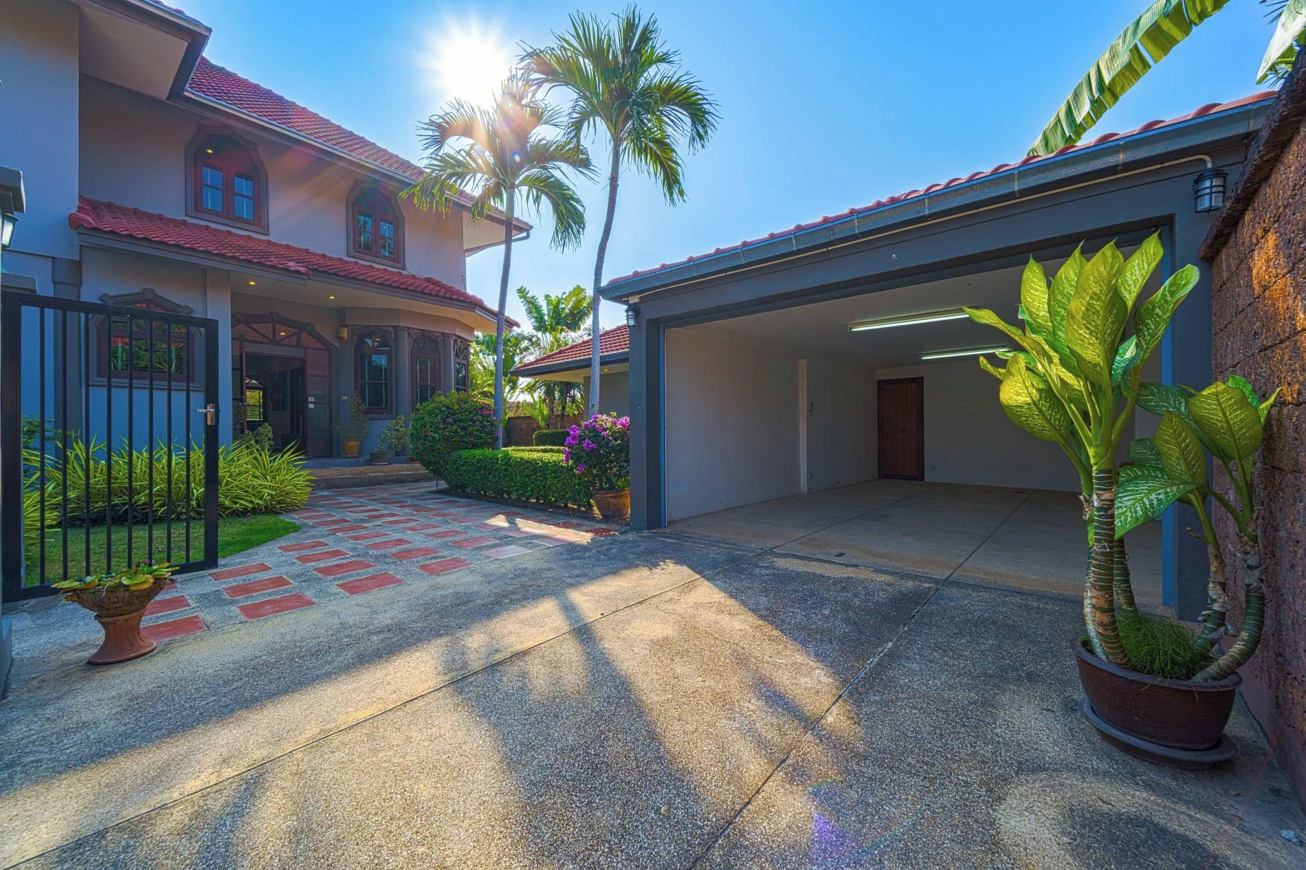 A two-story house with a covered driveway, palm trees, and a garage.