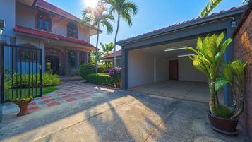 A two-story house with a covered driveway, palm trees, and a garage.
