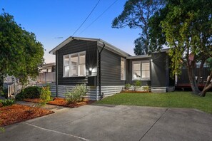 Ein eingeschossiges Haus mit Veranda, Garage und gepflegtem Rasen.