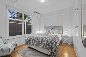 A bedroom with a bed, bedside tables, a window, and a wardrobe.